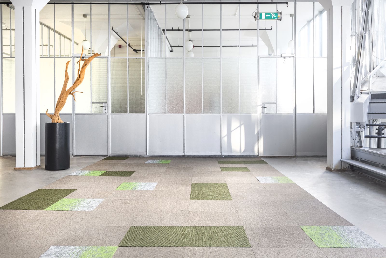 Lichtgrijze vloer met losse groene tapijttegels in een open kantoorruimte