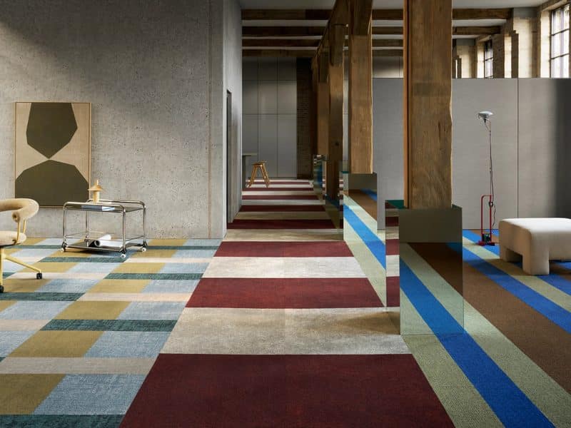 Loft met banen tapijttegels in rood, blauw, geel en grijs, tussen houten kolommen