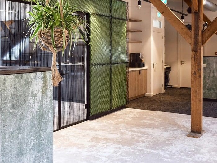 Ontvangstruimte met een groen gaaspaneel en een houten spant, op een licht tapijt